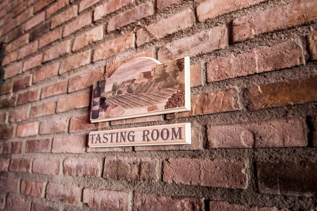 A quaint tasting room sign on a rustic brick wall creates a vintage ambiance.