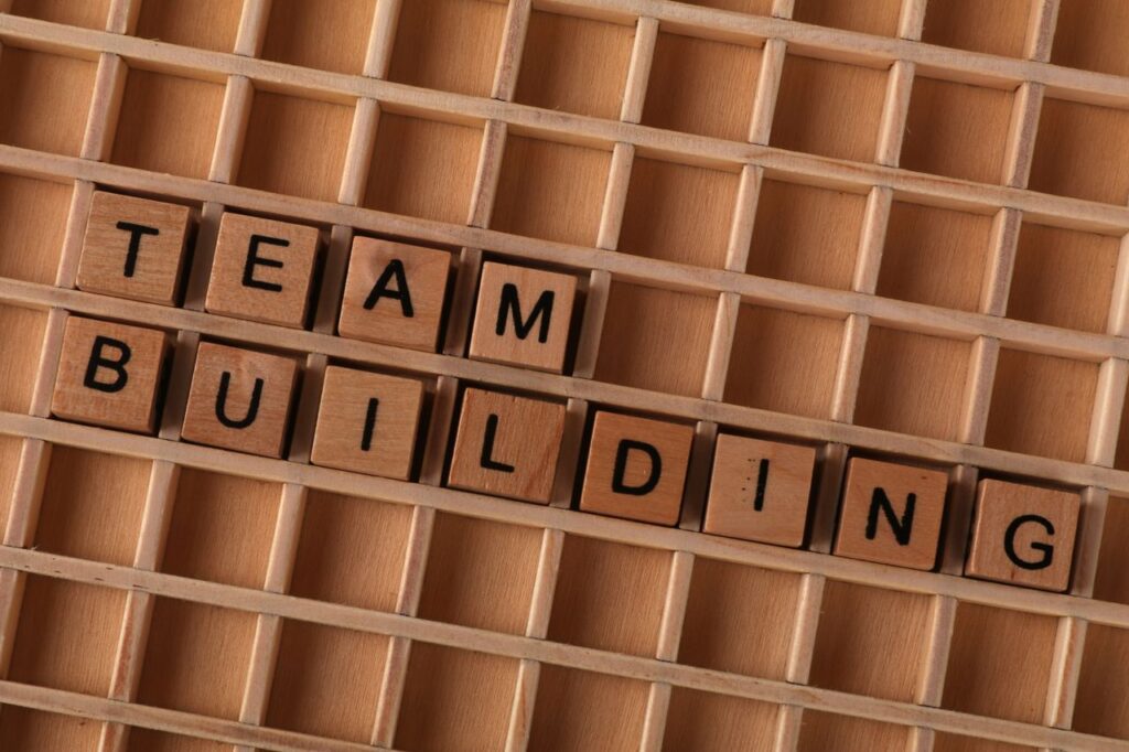 Wooden letter tiles spelling 'Team Building' on a grid surface to symbolize collaboration.