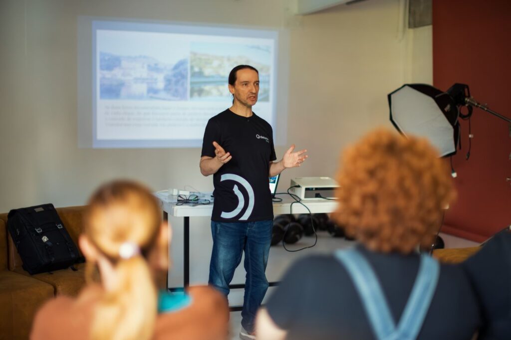 A speaker gives a presentation to a small audience in an office room, using a projector.